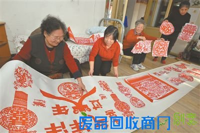 张培华老人（左一）展示“百羊图”剪纸作品。